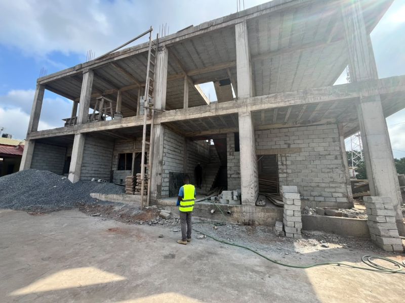 A two-story building construction with a reinforced concrete frame and grey blockwork walls.