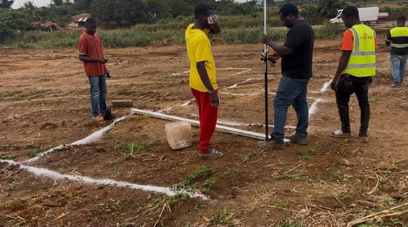 Site team carrying out building setting out with surveying equipment and marked foundation lines before excavation.