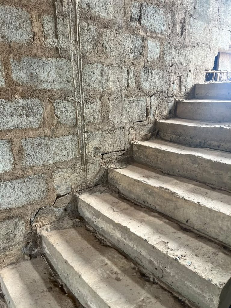 Cracked blockwork beside a staircase before wall crack repairs in Ghana