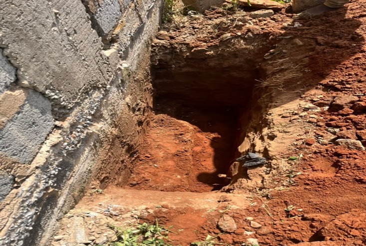 Excavation exposing the existing foundation beside a blockwork wall
