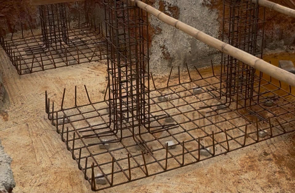 Foundation reinforcement mesh and column starter bars positioned in an excavated footing